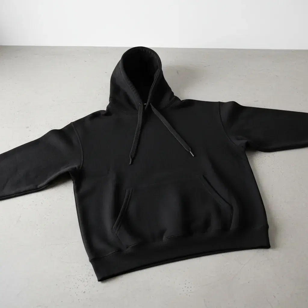 Flat-lay of a heavyweight black hoodie on a concrete surface